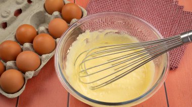 Pişirmek için malzemeler. Yumurta, hamur ve çırpı mutfak masasında.
