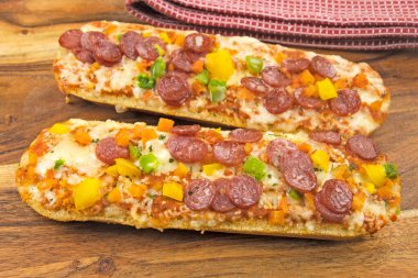 Tahta arka planda salamlı, peynirli ve sebzeli pizza.