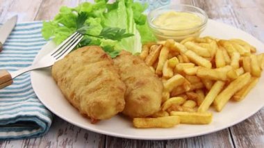 Balık ve patates kızartması, marul, sos ve maydanoz.