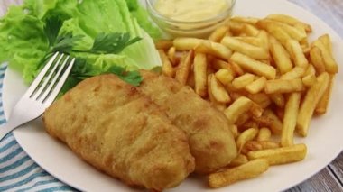 Balık ve patates kızartması, marul, sos ve maydanoz.