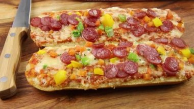 Tahta arka planda salamlı, peynirli ve sebzeli pizzalı sandviç. 