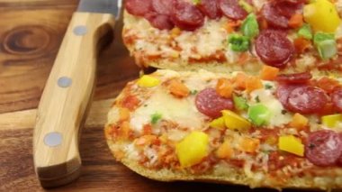 Tahta arka planda salamlı, peynirli ve sebzeli pizzalı sandviç. 