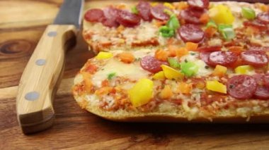 Tahta arka planda salamlı, peynirli ve sebzeli pizzalı sandviç. 
