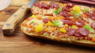 Tahta arka planda salamlı, peynirli ve sebzeli pizzalı sandviç. 