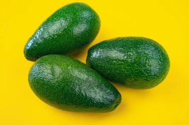 Sarı arka planda olgun avokadolar..