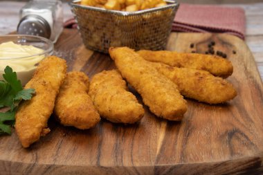 Sos ve patates kızartmasıyla kızartılmış kızarmış tavuk şeritleri. 