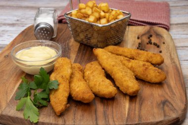 Sos ve patates kızartmasıyla kızartılmış kızarmış tavuk şeritleri. 