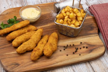 Sos ve patates kızartmasıyla kızartılmış kızarmış tavuk şeritleri. 
