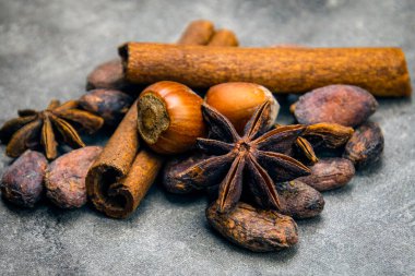 fındık, tarçın çubukları ve anason yıldızları koyu bir arka planda. Kış baharatları 