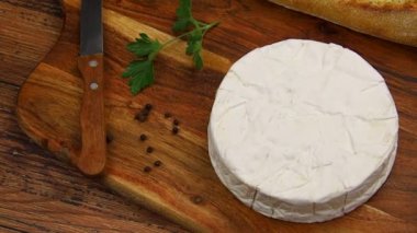 Tahtada bıçak, baharat ve ekmek olan camembert peyniri.