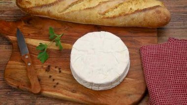 Tahtada bıçak, baharat ve ekmek olan camembert peyniri.