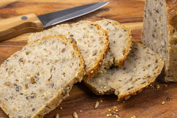 Tahtada tohum ve bıçakla kesilmiş ev yapımı ekmek.