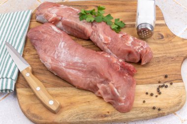 Kesme tahtasındaki çiğ domuz filetosu.