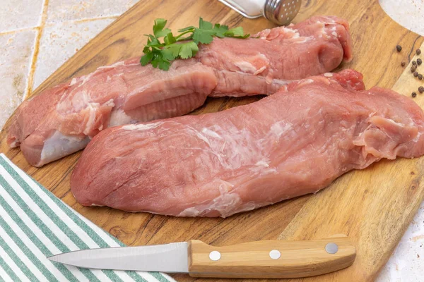 Kesme tahtasındaki çiğ domuz filetosu.