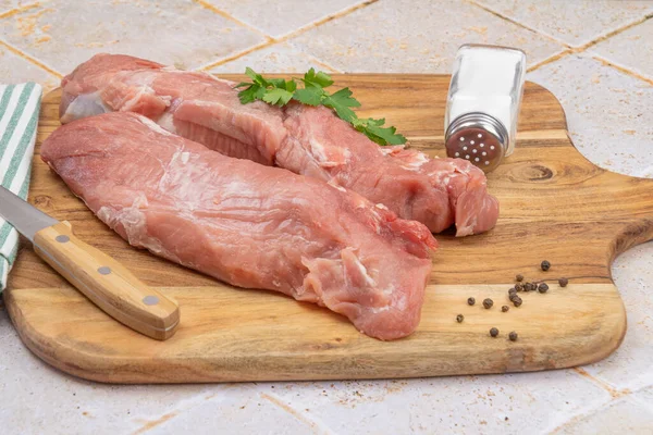 Kesme tahtasındaki çiğ domuz filetosu.