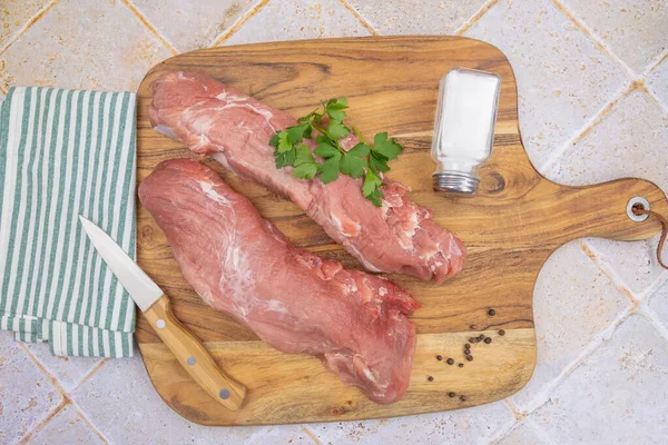 Kesme tahtasındaki çiğ domuz filetosu.