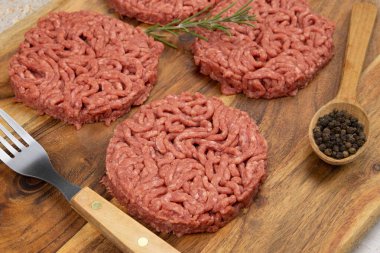 Kesme tahtasında birkaç çiğ hamburger.
