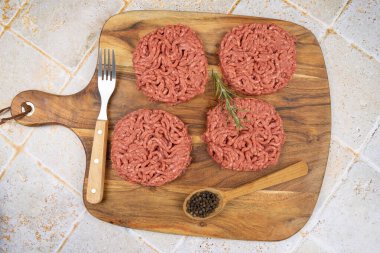 Kesme tahtasında birkaç çiğ hamburger.