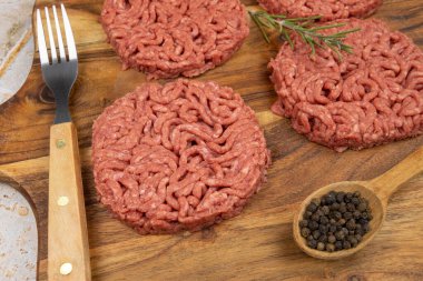 Kesme tahtasında birkaç çiğ hamburger.