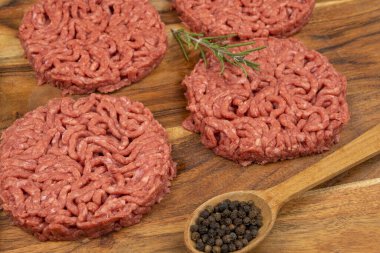 Kesme tahtasında birkaç çiğ hamburger.