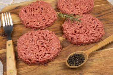 Kesme tahtasında birkaç çiğ hamburger.