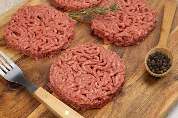 Kesme tahtasında birkaç çiğ hamburger.