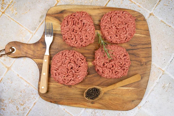 Kesme tahtasında birkaç çiğ hamburger.