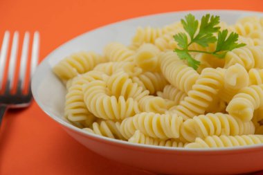 Turuncu arka planda tereyağlı makarna (fusilli)