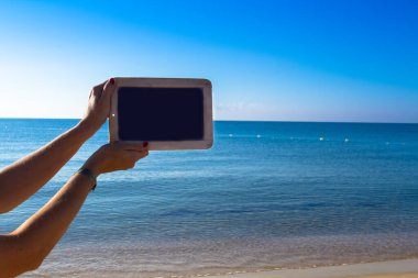 Kumsalda elinde boş bir karatahta tutan kadın