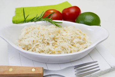 Beyaz kasede pilav ve masada sebze. 