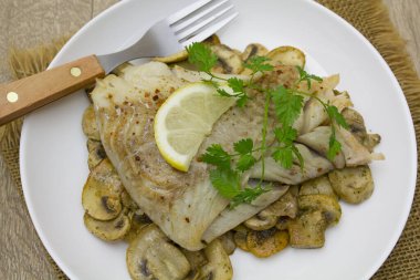 Mantarlı fırında balık, maydanoz ve limon.