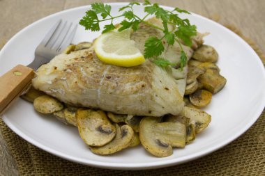 Mantarlı fırında balık, maydanoz ve limon.