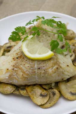 Mantarlı fırında balık, maydanoz ve limon.