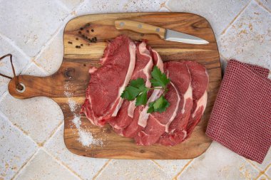 Baharatlı çiğ et ve ahşap kesme tahtasındaki otlar. 