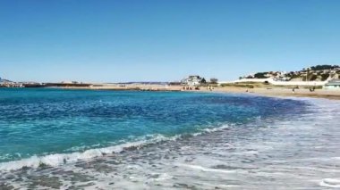 Güneşli bir günde dalgalı deniz manzarası ve kumlu plaj