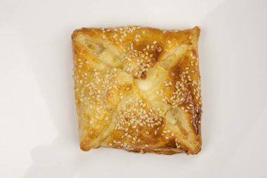 Beyaz arka planda izole edilmiş susam tohumlu puf böreği.