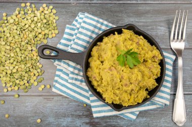 Gri arka planda bir tavada bezelye püresi ve taze bezelye.