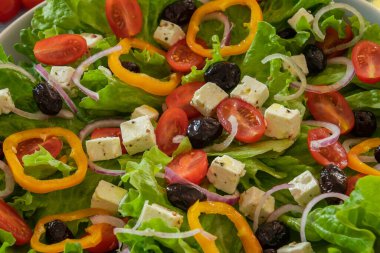 Sebzeli yeşil salata ve masada beyaz peynir.