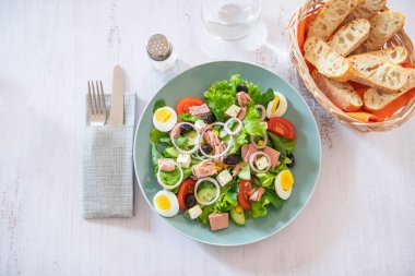 Ton balıklı salata, yumurta, sebze ve peynir ahşap masada.