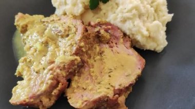 Patates püreli bir tabakta kızarmış domuz eti dilimi.