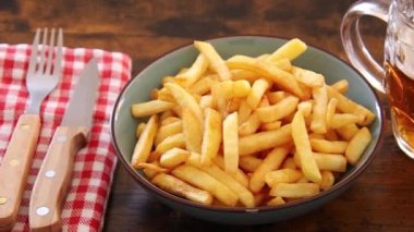 Bir tabak patates kızartması ve bir bardak biranın üst görüntüsü.