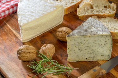 Tomme de Savoy ve Tomme. Tahtada cevizli yabani sarımsaklı.