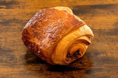 Tahta arka planda izole edilmiş taze kruvasan.