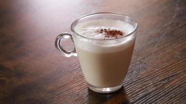 Kapuçino, ahşap masaya kakao serpiştirilmiş.