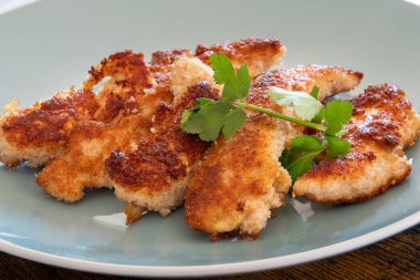 Tabakta ekmek kırıntıları olan kızarmış tavuk.