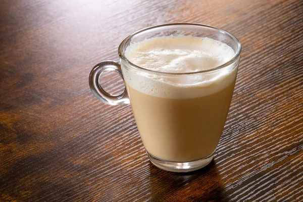 Ahşap bir masada bir bardak kapuçino.