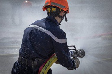Tatbikat sırasında elinde yangın hortumu tutan kişi.