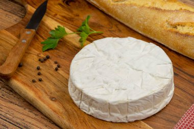 Ahşap bir tahtanın üzerindeki camembert peynirini ekmek ile kapat.