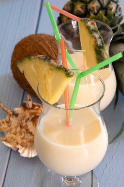 Üzerinde hindistan cevizi ve ananas olan bir masanın üzerindeki bir bardak Pina Colada 'nın manzarası.