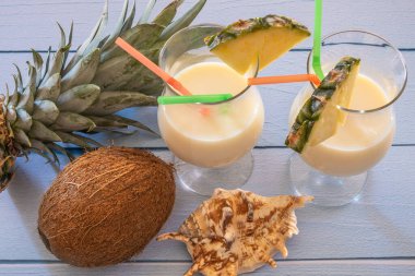 Üzerinde hindistan cevizi ve ananas olan bir masanın üzerindeki bir bardak Pina Colada 'nın manzarası.